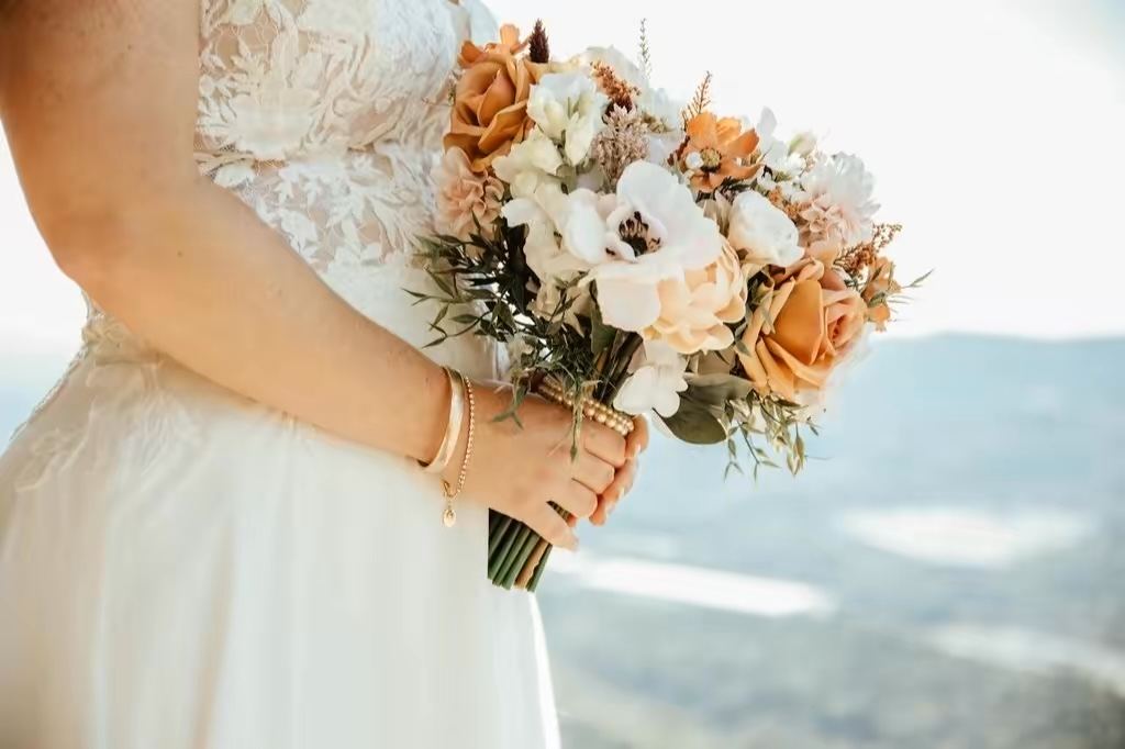 Close-up of bridal bouquet and hand showing even tan